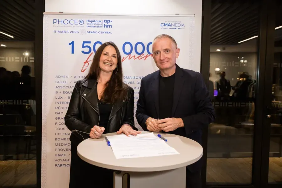 Signature d’une convention devant le kakémono « 1 500 000 mercis », qui liste les mécènes du projet, Aroma-Zone en tête.