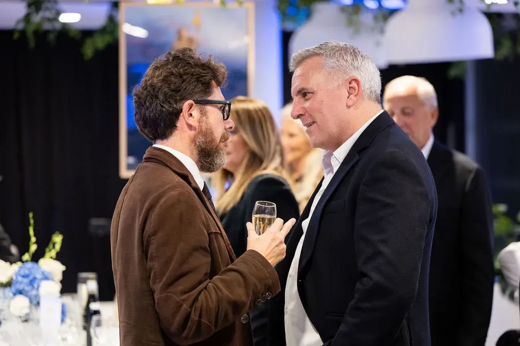 Deux invités en pleine conversation, une coupe à la main, pendant le cocktail.