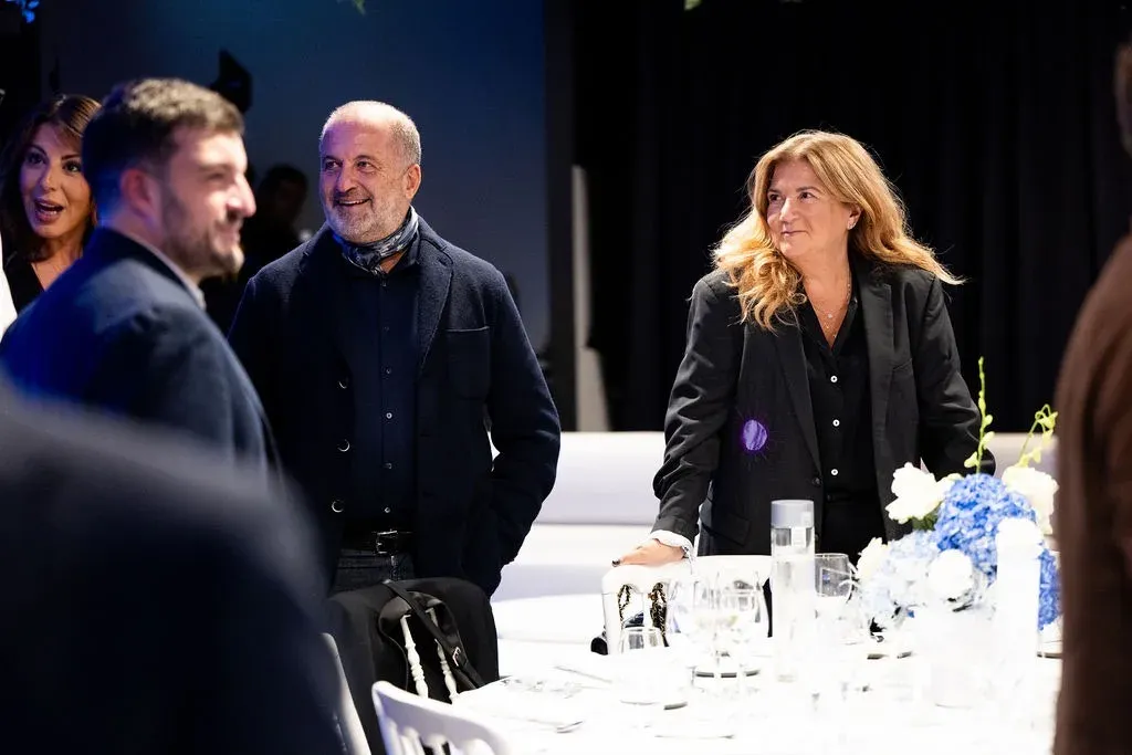 Deux invités posent dans la salle du dîner, les tables dressées derrière eux.