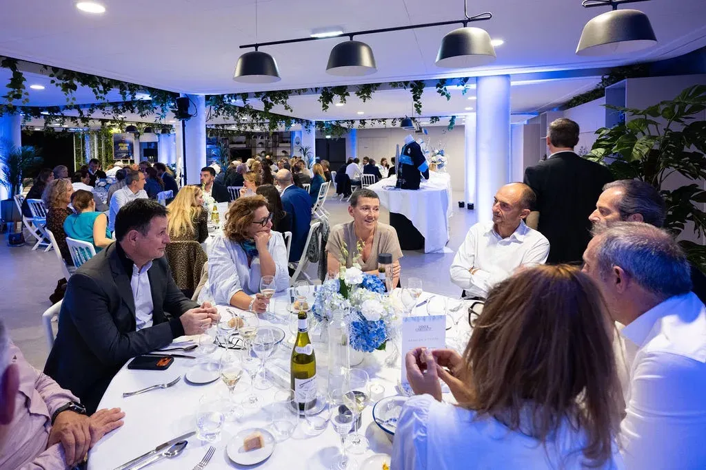 Vue d’ensemble du dîner : les tables rondes, les hortensias bleus et blancs, la salle comble.