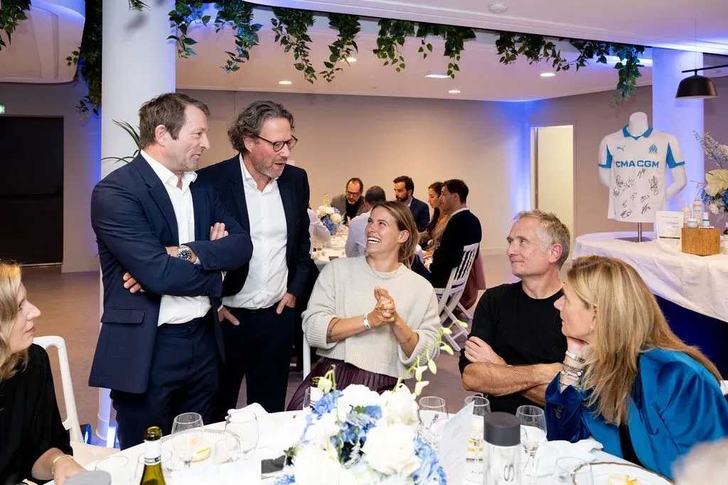 Des invités debout autour d’une table, devant le maillot de l’OM dédicacé.