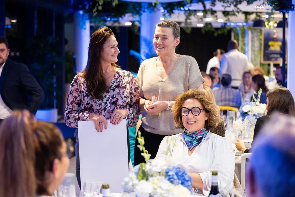 Trois invitées réunies pendant la soirée, au milieu des tables.