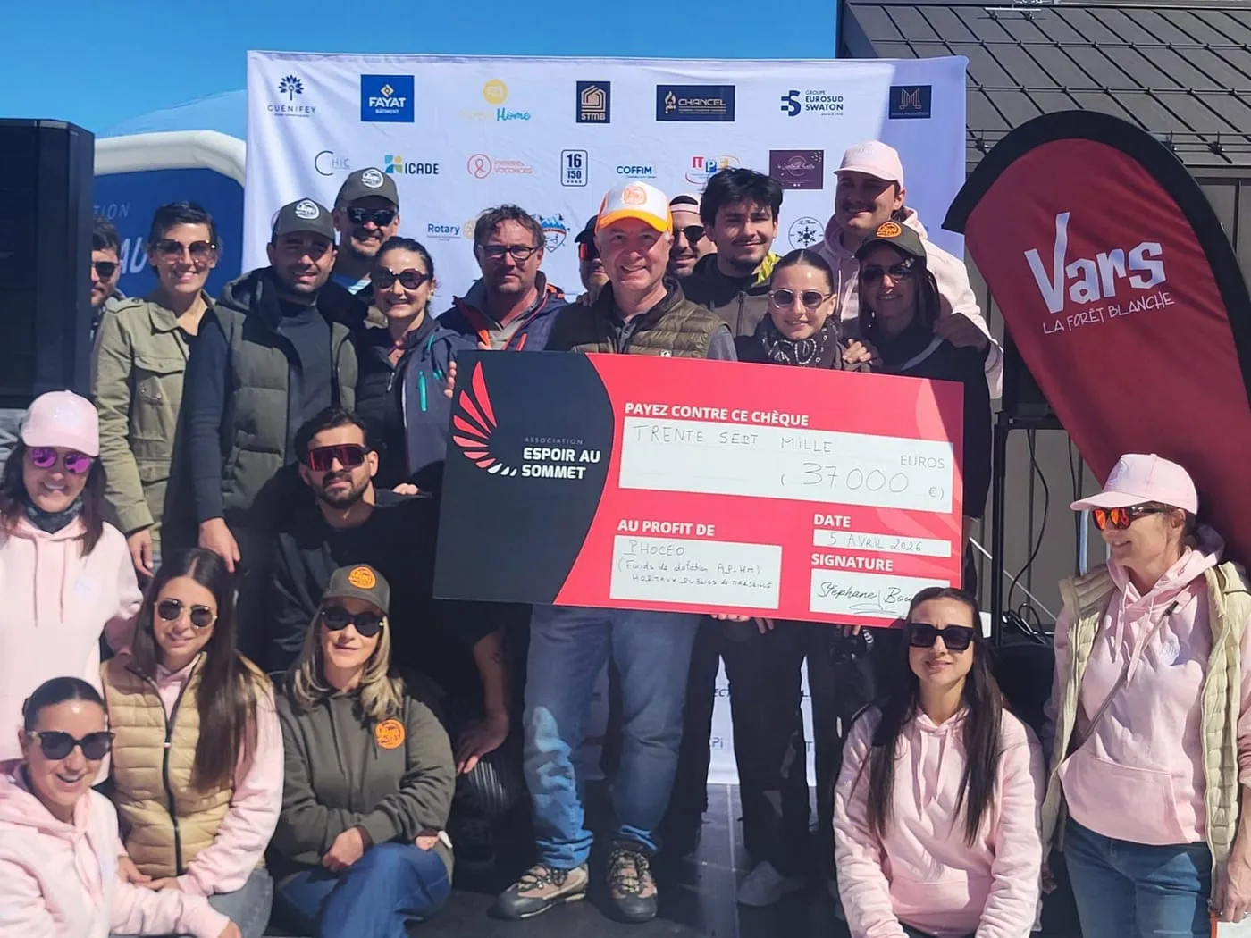 Une trentaine de bénévoles et de partenaires réunis à Vars autour du chèque de 37 000 €, devant le mur des partenaires de l’événement.
