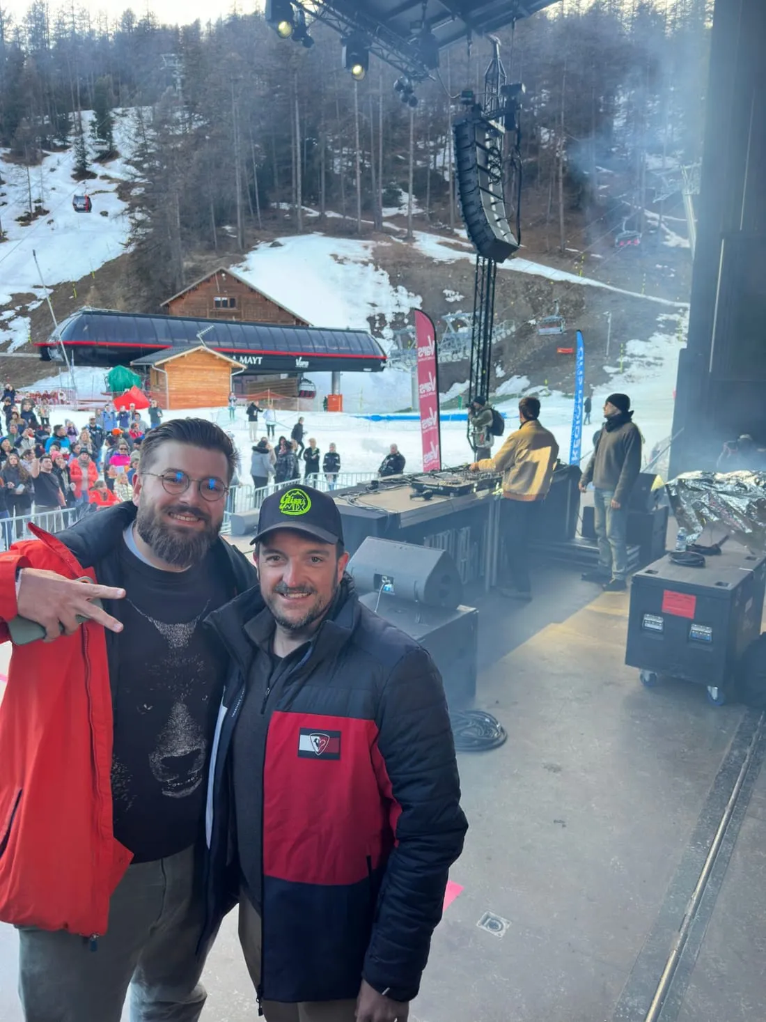 Deux participants posent au bord de la scène pendant le set du DJ, le public massé derrière les barrières.