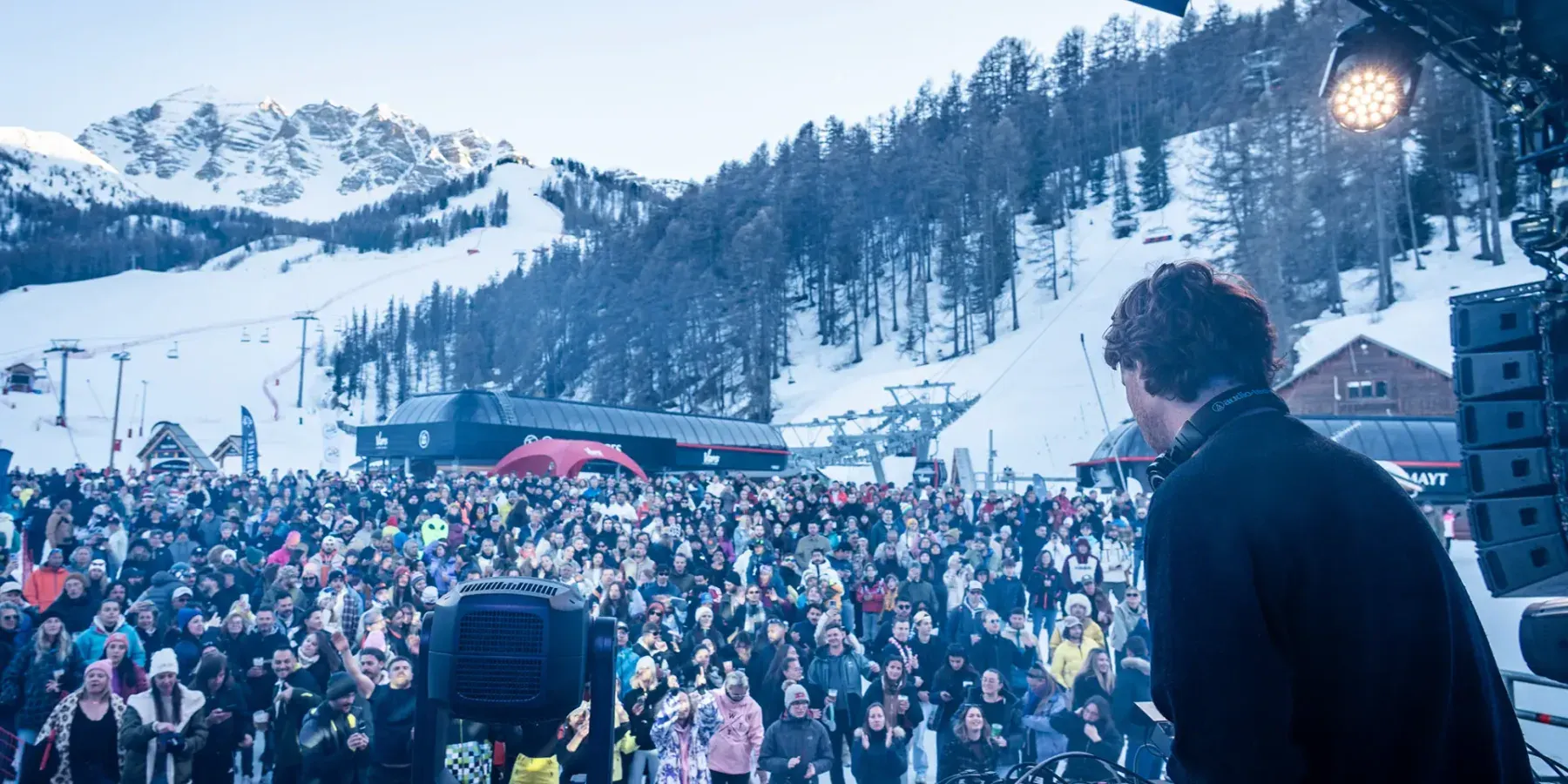 Vue depuis la scène : un DJ face à plusieurs centaines de personnes réunies au pied des pistes.