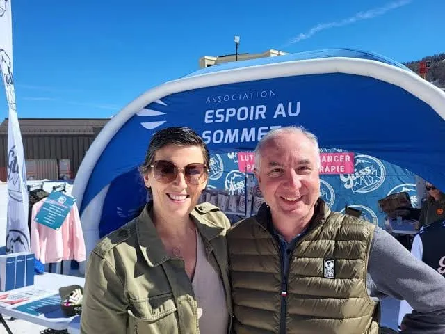 Deux personnes devant le stand d’Espoir au sommet, où l’on lit « lutter contre le cancer par le sport thérapie ».