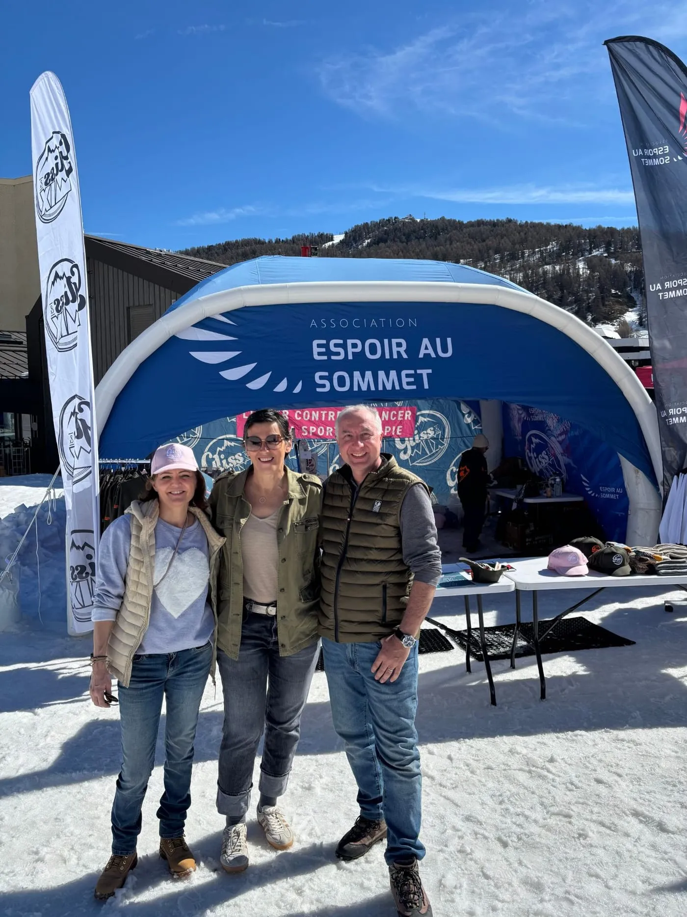 Trois personnes devant la tente gonflable de l’association Espoir au sommet, sur la neige, à Vars.
