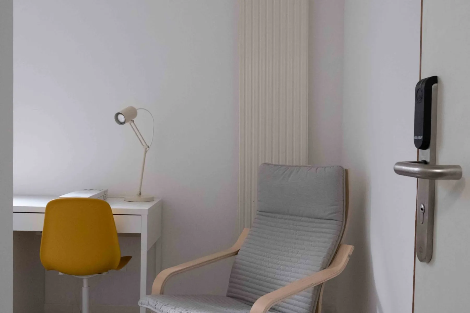 Une chambre de garde rénovée pour les internes : bureau, chaise, fauteuil et lampe.