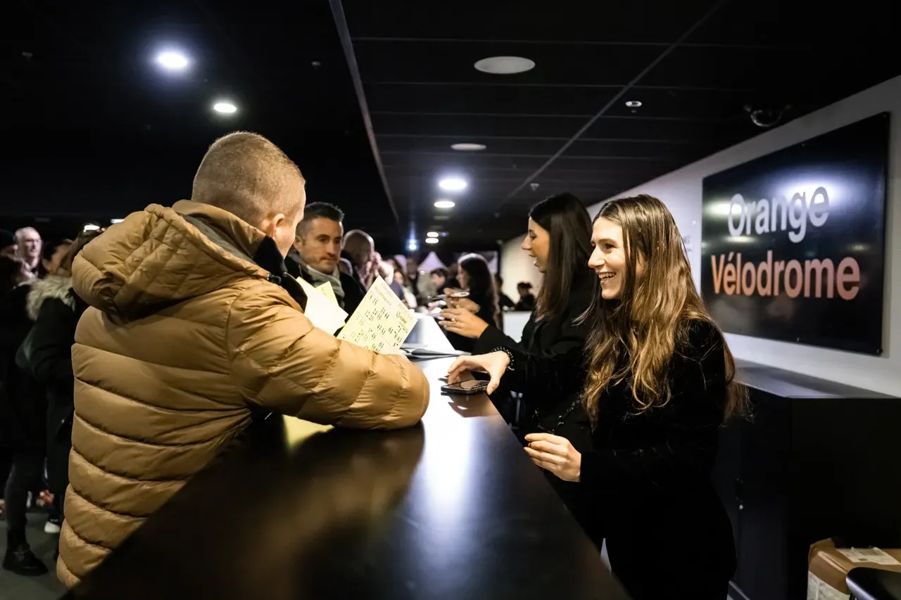 Au comptoir d’accueil de l’Orange Vélodrome, une bénévole remet ses cartons à un participant.